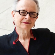 Photo of Barbara Kirshenblatt-Gimblett in black shirt with red trim and black glasses.