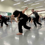 Student dancers audition in a brightly lit room with mirrors.