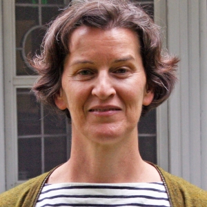 A woman with short hair, striped shirt, and green cardigan.