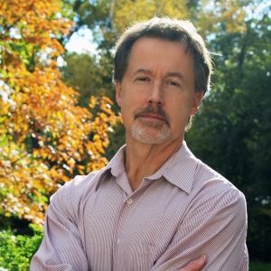 A man with a goatee and pink button-down shirt.